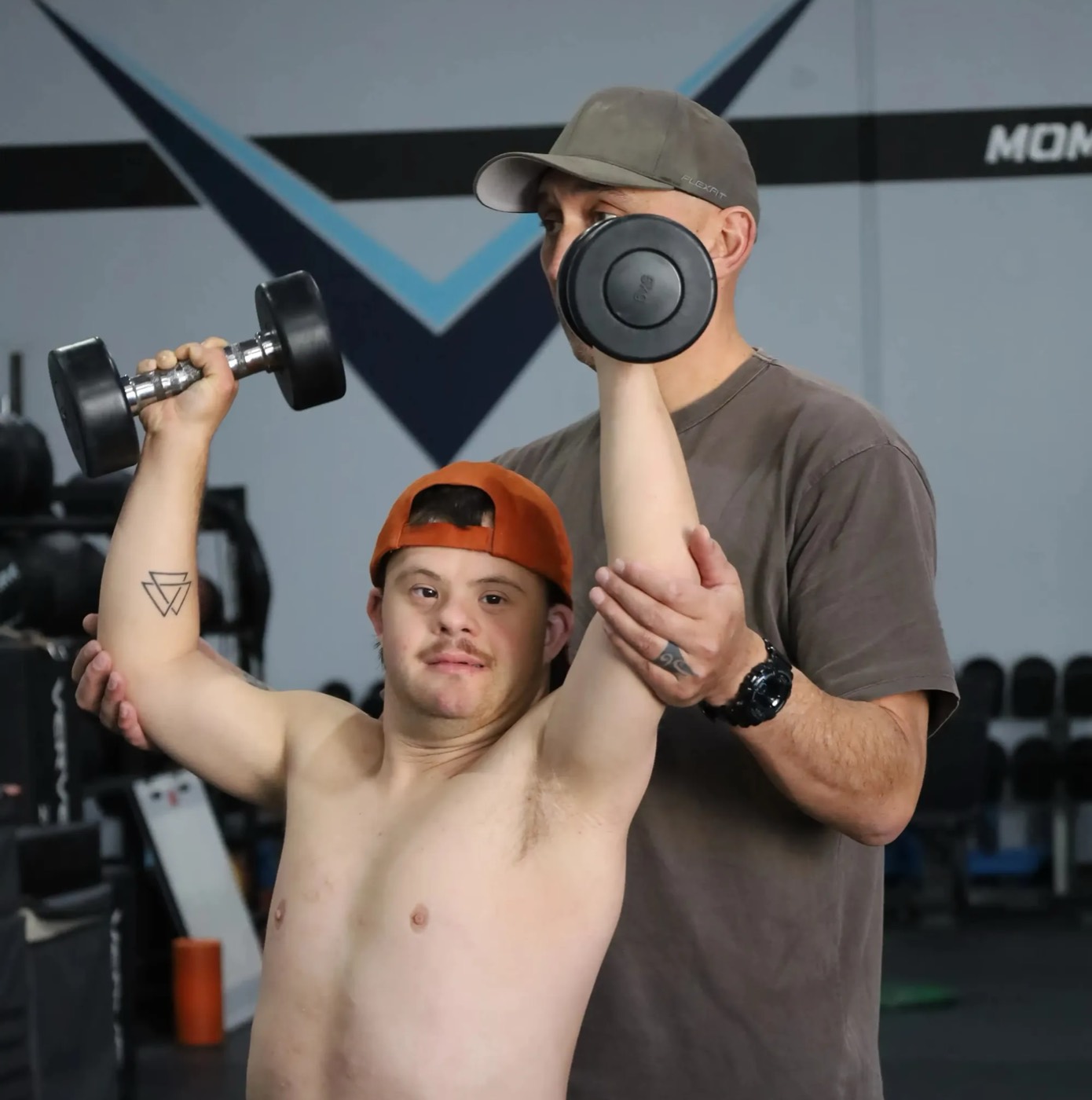 A participant doing a dumbbell workout with support from their Mate
